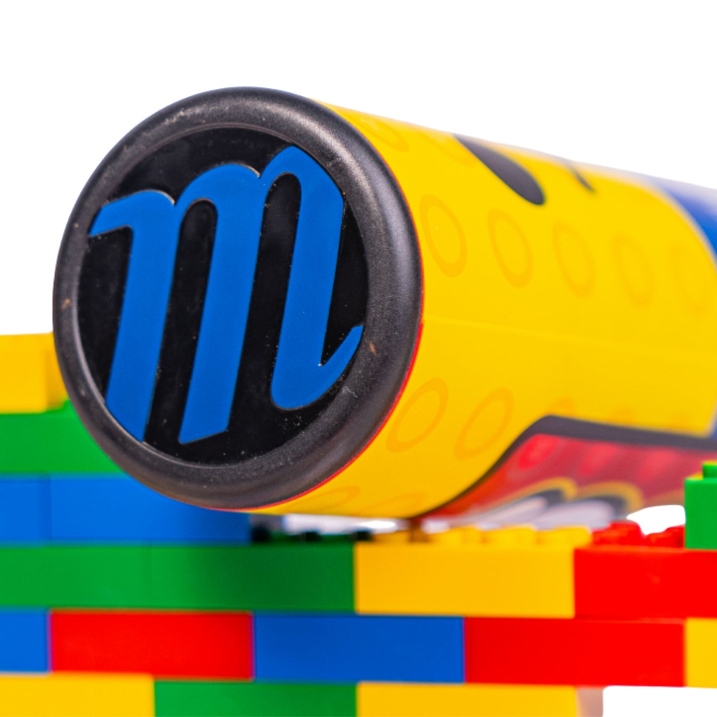 A photo of the Marucci Block Party 12.75" 2PC Loaded USSSA Slo-pitch Bat in colour blue, red and yellow. Multi colour Lego pieces in the background.