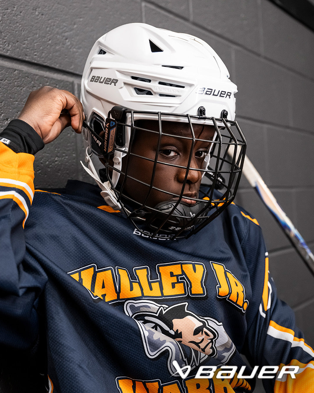 A photo of a child wearing a white Bauer RE-AKT 3D Helmet. 