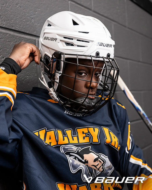 A photo of a child wearing a white Bauer RE-AKT 3D Helmet. 