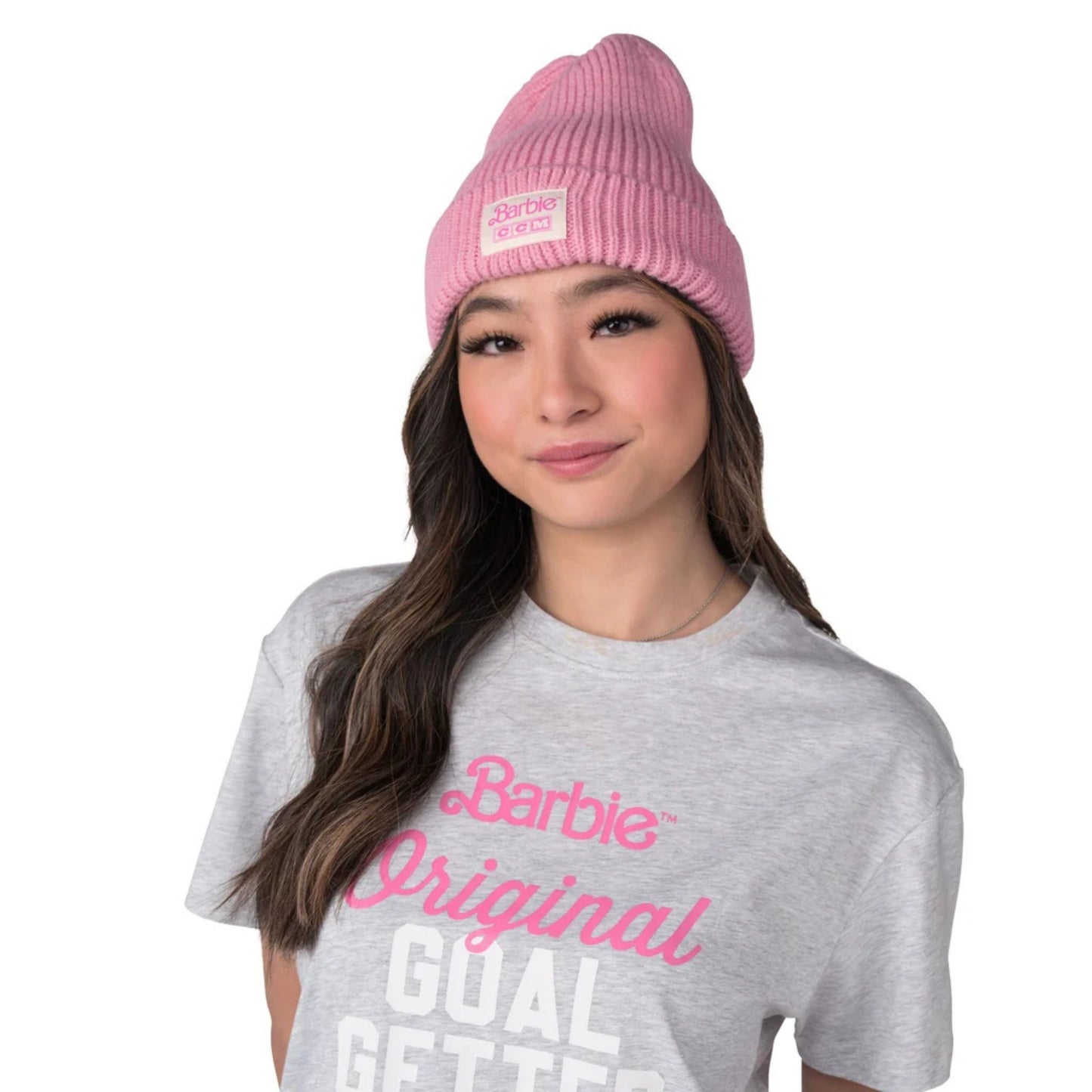 A photo of a woman wearing a grey Barbie shirt and the pink Barbie™ x CCM Cuffed Adult Beanie