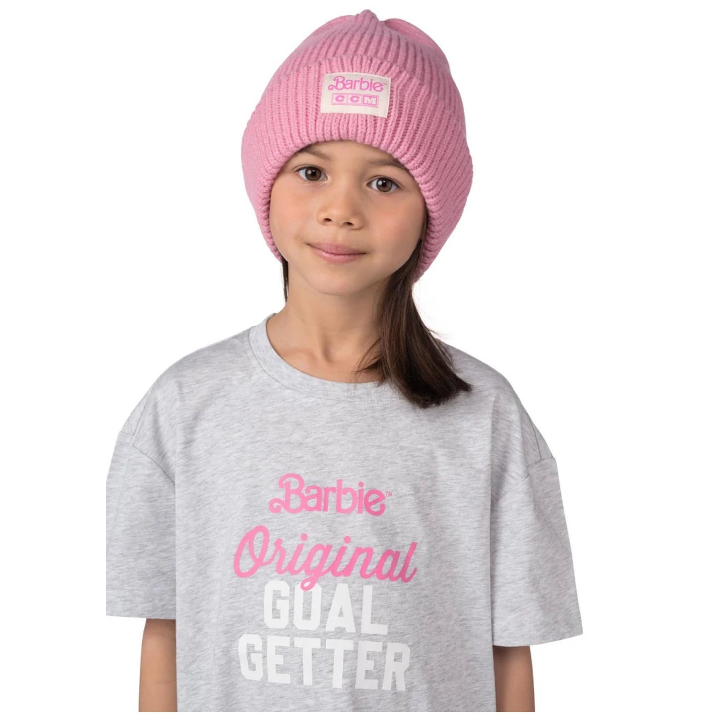 A photo a child in a Grey Barbie shirt wearing the Barbie™ x CCM Cuffed Youth Beanie in colour pink.