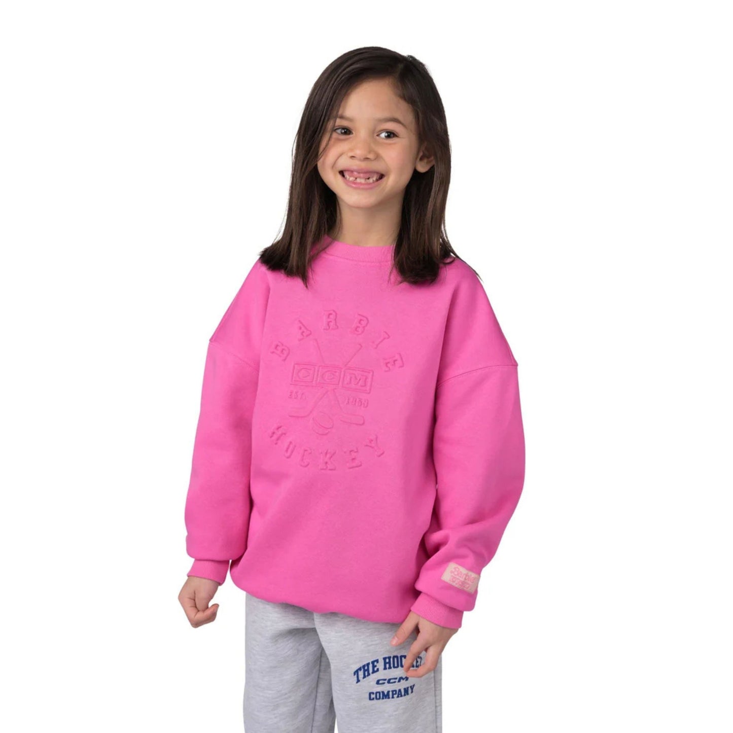A photo of a child wearing a pink Barbie™ x CCM Pink Embossed Youth Crewneck.