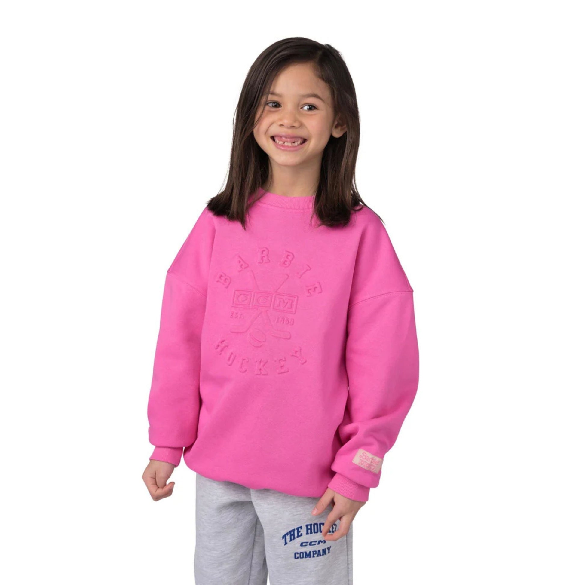 A photo of a child wearing a pink Barbie™ x CCM Pink Embossed Youth Crewneck.