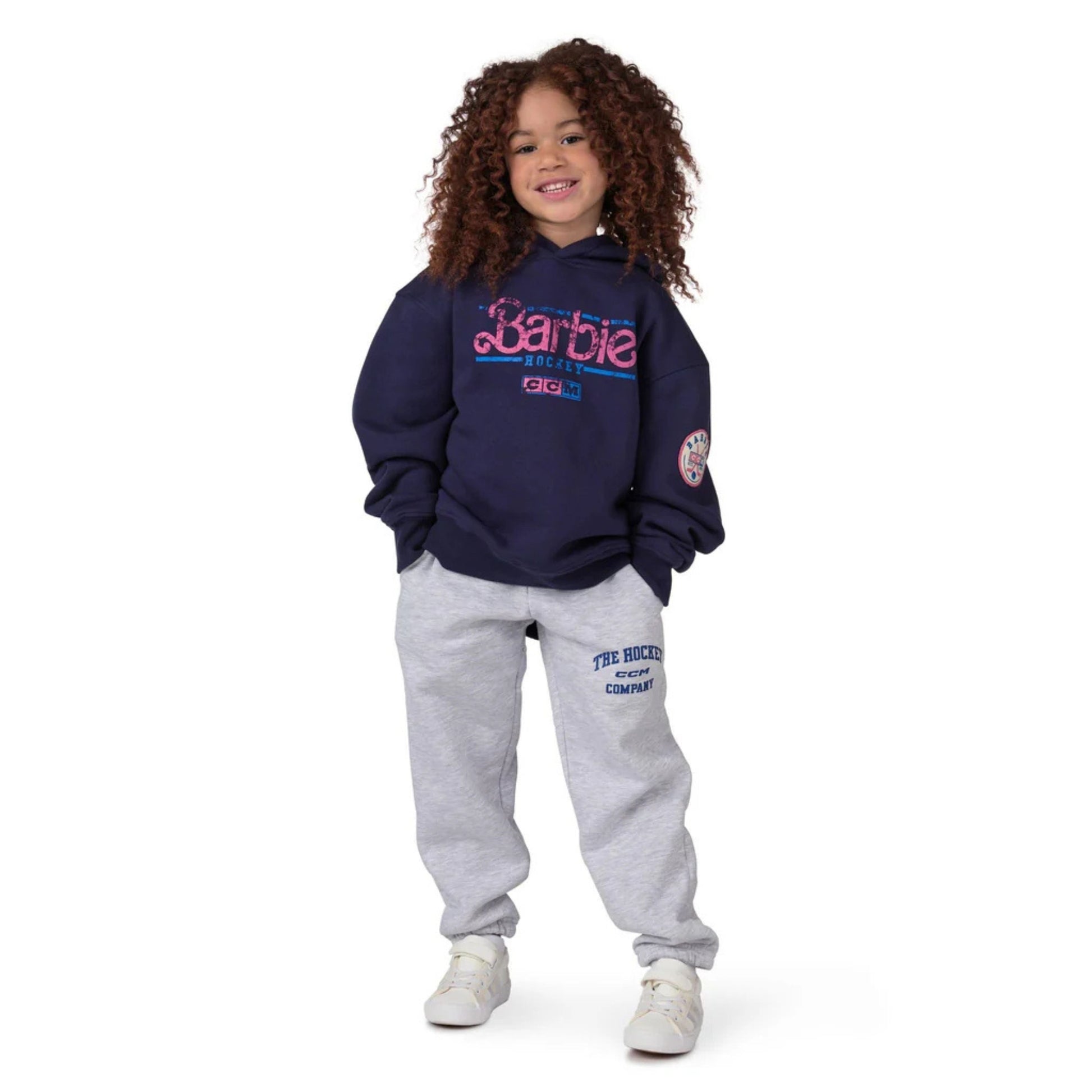 A photo of a child wearing grey sweat pants and Barbie x CCM Navy Pullover Youth Hoodie in colour navy.