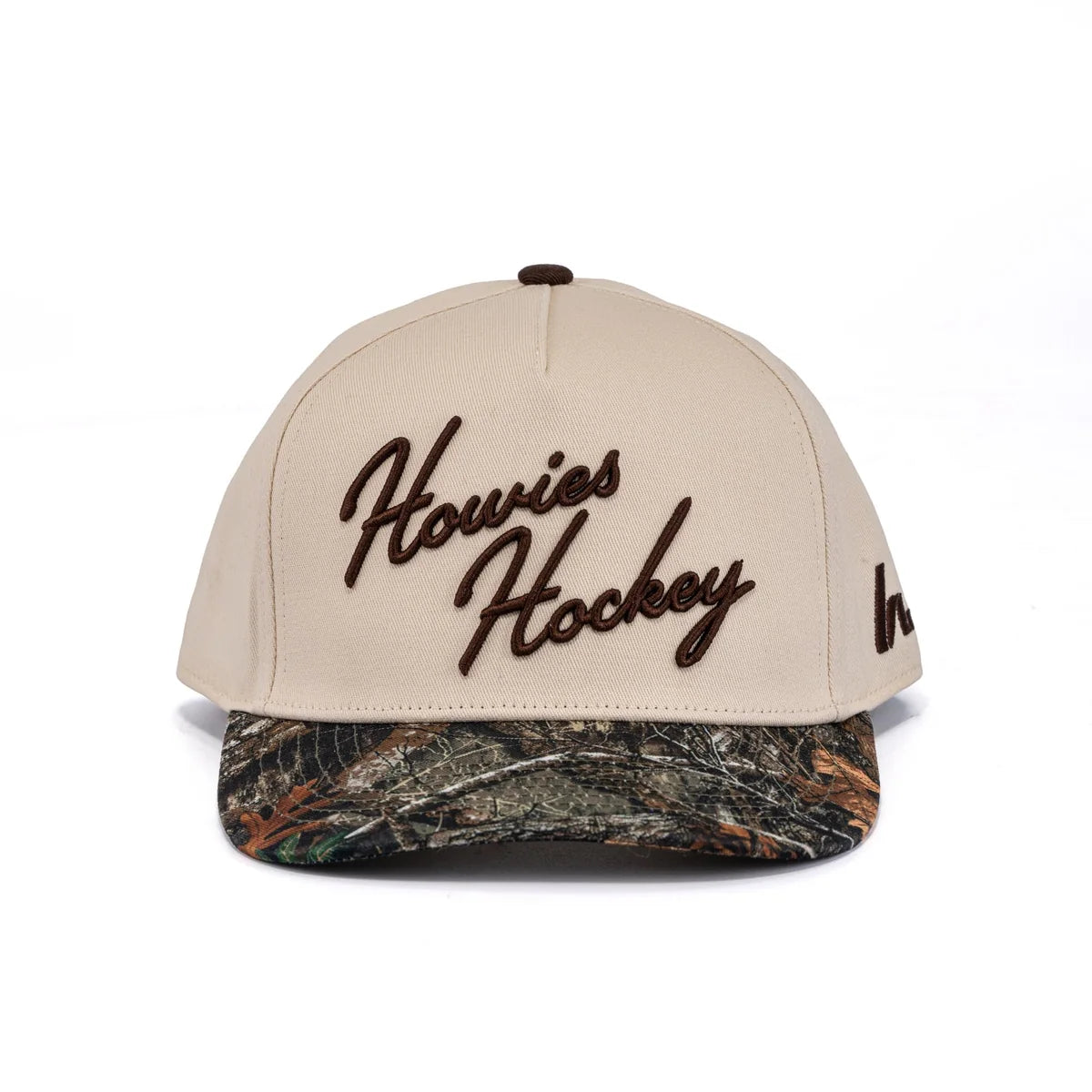 A photo of the Howies The Sharpshooter Lid in colour cream with a brown logo and a camo brim.