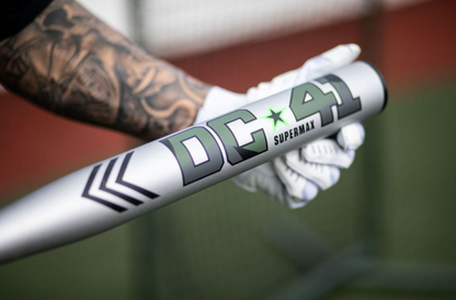 A photo of the 2024 Miken DC-41 SUPERMAX USSSA Slo-Pitch Bat - Source Exclusive in silver colour with dark green text being held by batter