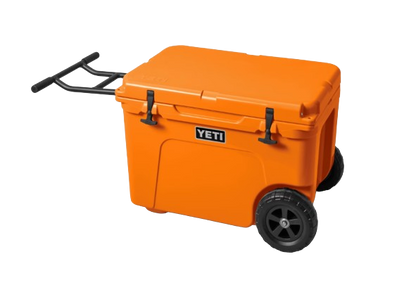 A photo of the Yeti Tundra Haul Wheeled Cooler in colour king crab orange, front, closed view. Extended handle bars.