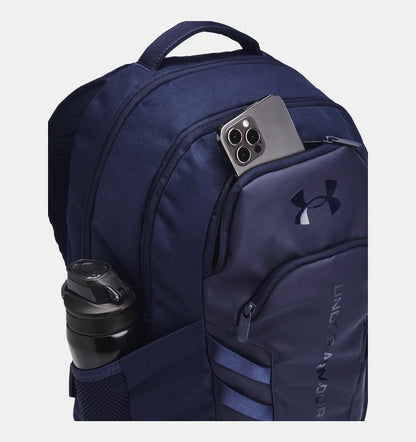 Navy blue backpack with side view of mesh pocket with water bottle and sell phone in second pocket.