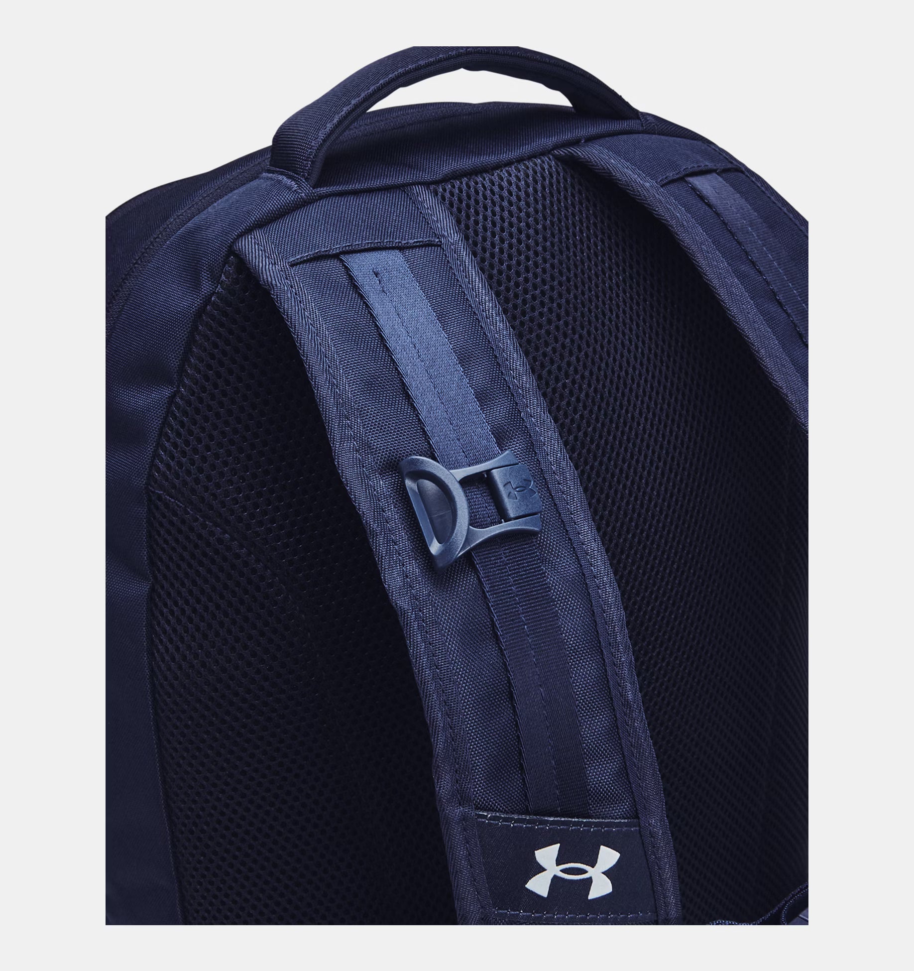 Navy blue backpack with Under Armour logo on back strap. Top carry handle in navy.