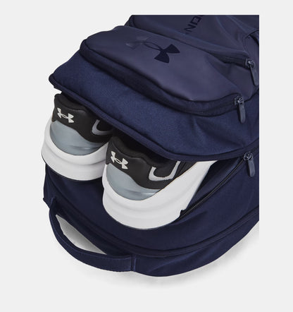 Navy Under Armour backpack shown with running shoes in second compartment.